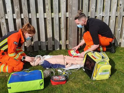 Paramedic Sophie And Dr Jono Training on a manikin, surrounded by kit bags