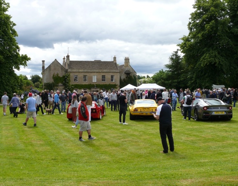 A photo of a house and cars, with people walking around