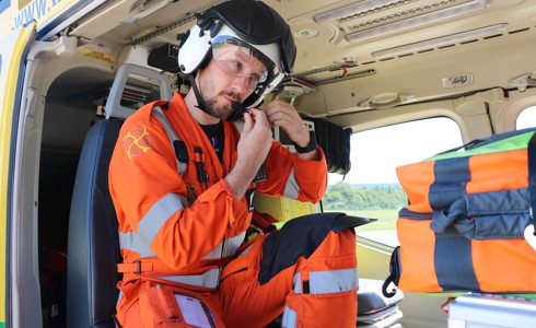 A photo of doctor Jono Holme securing his helmet, whilst sat in the helicopter