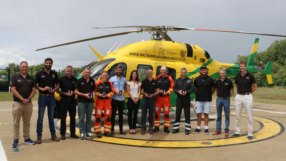 A photo of critical care paramedics and pilots in front of the Bell-429 helicopter on the helipad holding Platinum Jubilee award medals.