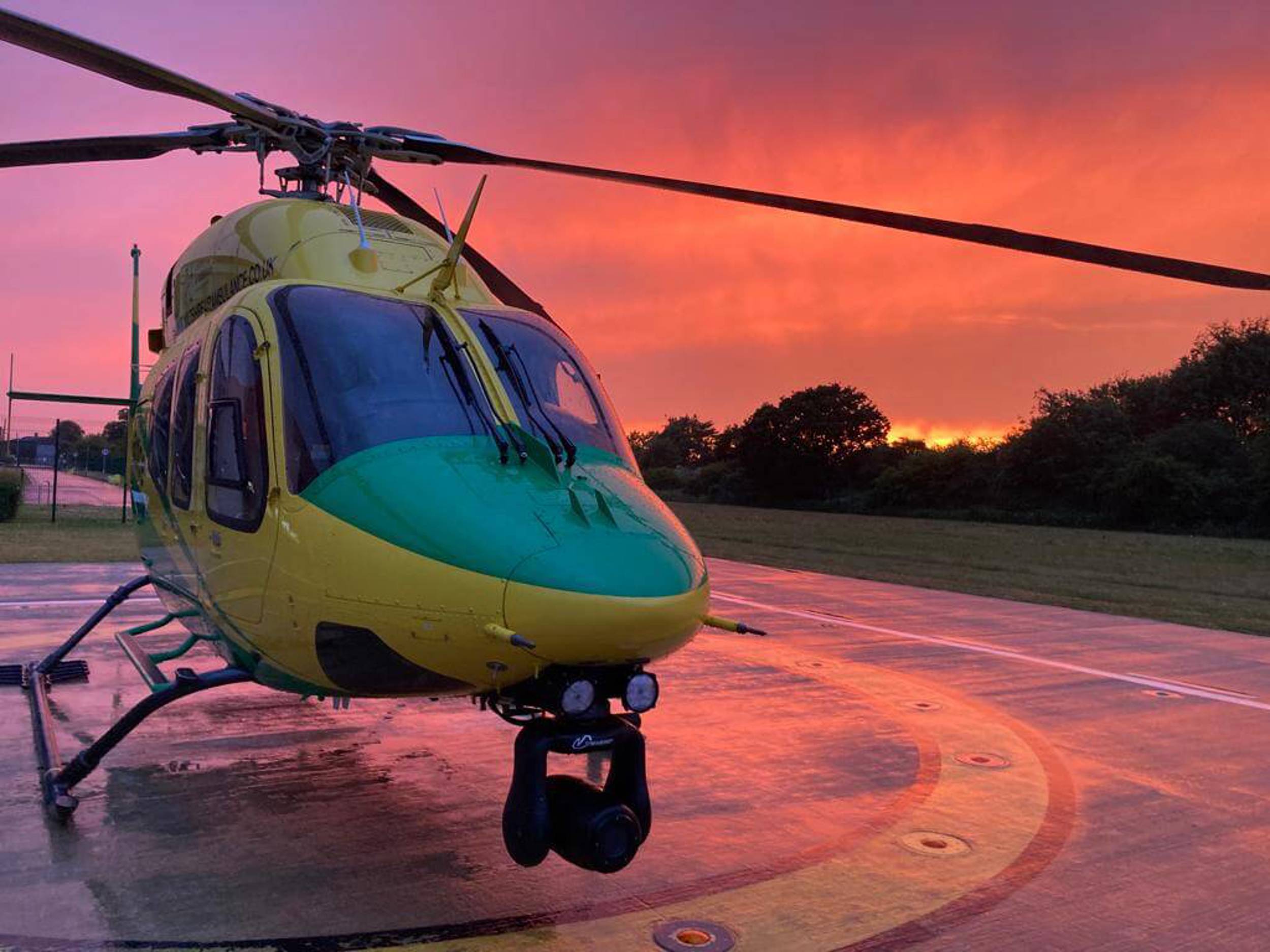 A beautiful red and pink sunset with the helicopter sat on the helipad.