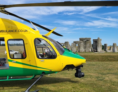 A yellow and green helicopter landed near Stonehenge