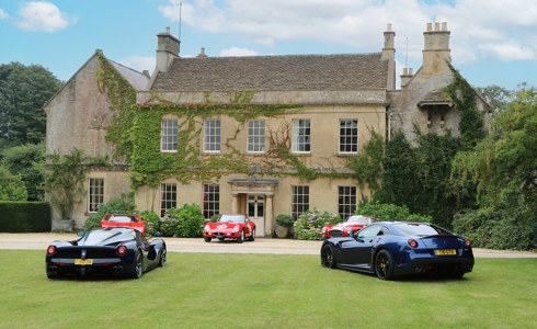 The exterior of Middlewick House, with five sports cars parked on the lawn in front