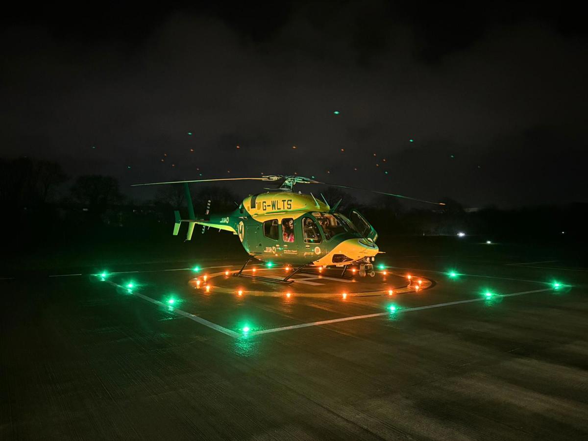 Wiltshire and Bath Air Ambulance Charity's new look helicopter on their helipad at night with the lights on